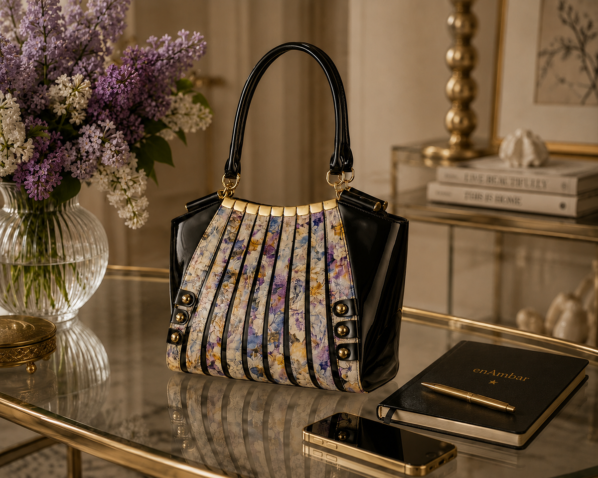 Artisan embroidered leather handbag in multicolor floral print with black patent leather back and sides, on a glass table
