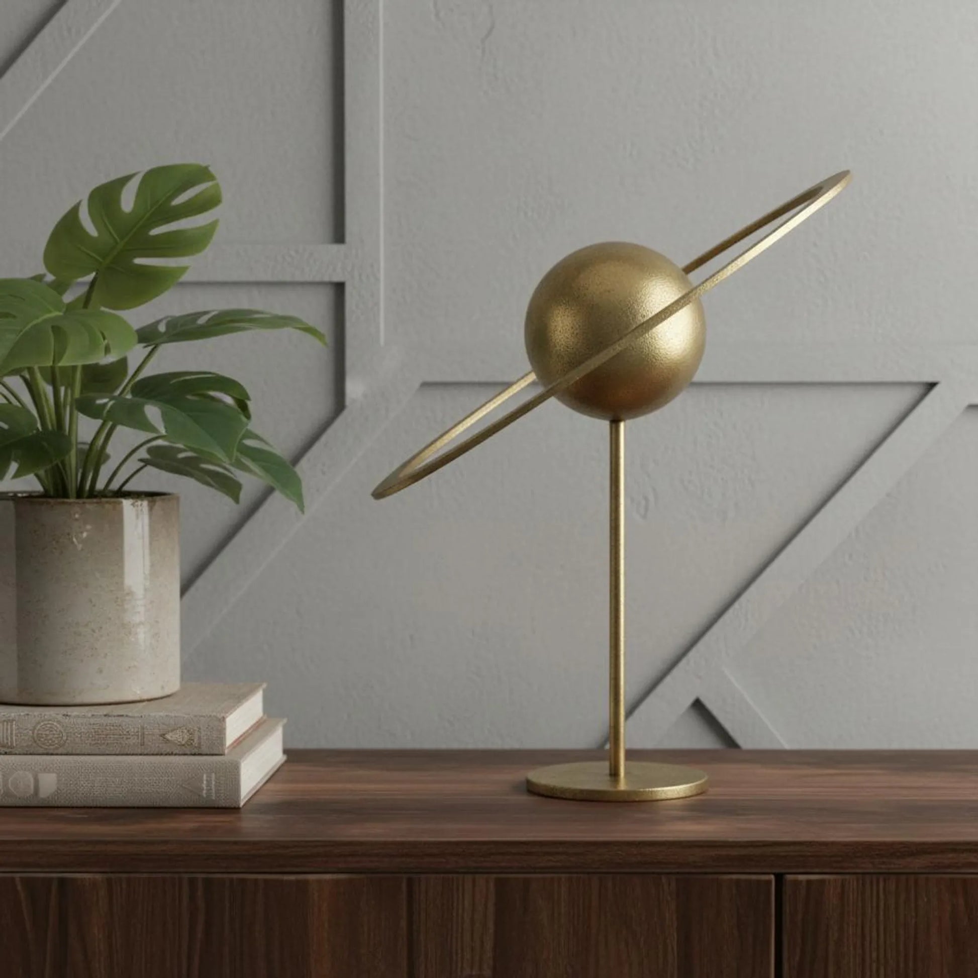 Gold iron solar system sculpture on brass stand, styled on wood console with books and plant