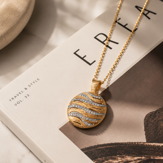 Gold cubic zirconia wave pendant on a fashion book