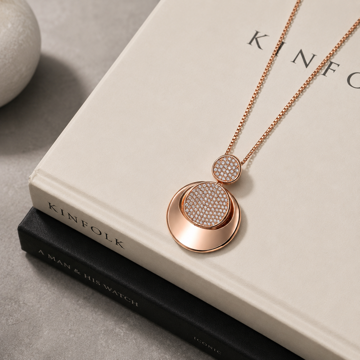 Rose gold micro pavé round pendant on a linen-bound book