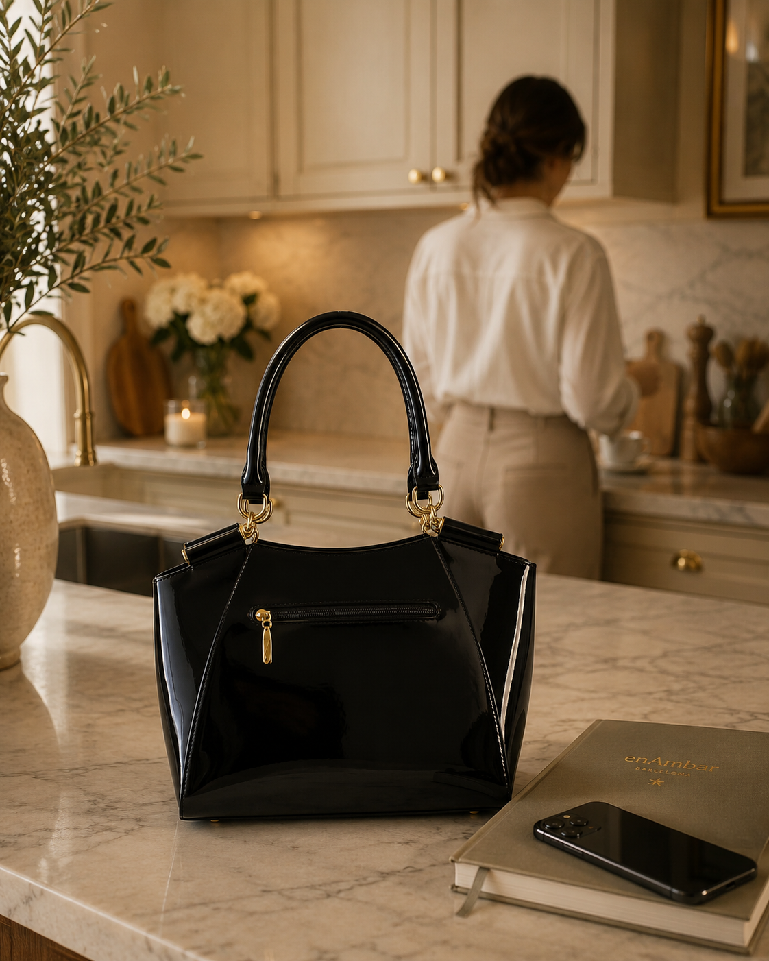 Artisan embroidered leather handbag in black patent leather with gold-tone hardware, in an elegant kitchen